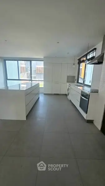 Modern kitchen with sleek white cabinetry and large windows for natural light.