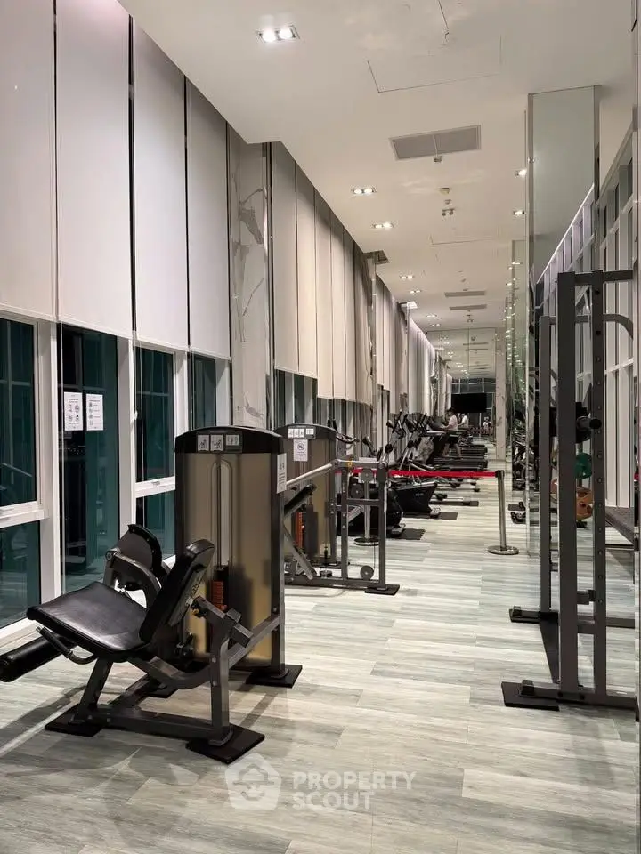 Modern gym with state-of-the-art equipment and floor-to-ceiling windows in luxury residential building.