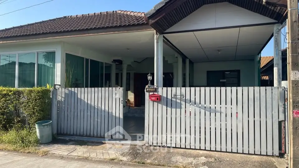 Charming single-story house with gated entrance and lush greenery