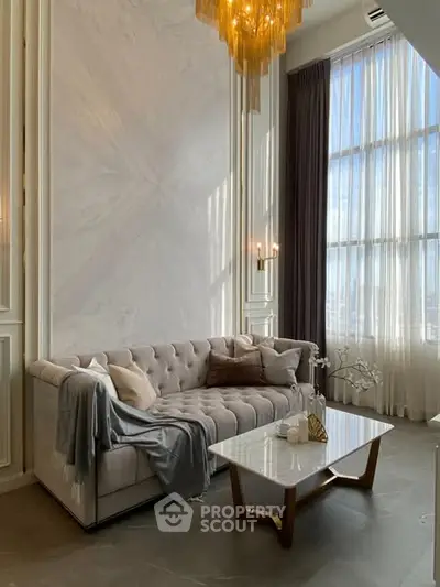 Luxurious high-ceiling living room with elegant sofa and marble coffee table, featuring a stunning chandelier.