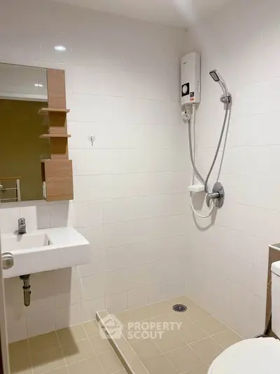 Modern bathroom with sleek fixtures and white tiles, featuring a shower and compact sink.