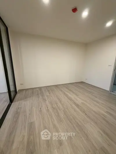 Spacious empty room with wooden flooring and bright lighting, ideal for customization.