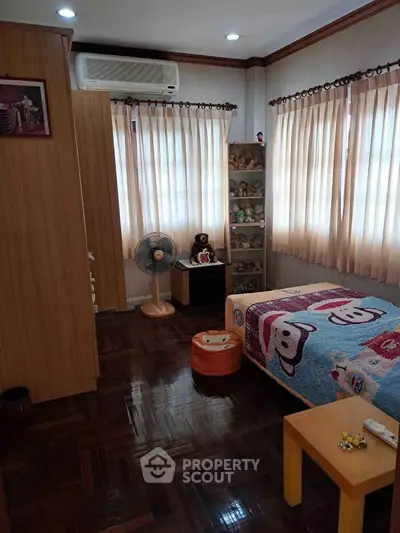 Charming bedroom with wooden flooring, cozy decor, and ample natural light, perfect for a child's retreat.