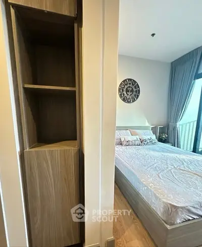 Modern bedroom with stylish decor and balcony view, featuring a cozy bed and elegant wooden shelving.
