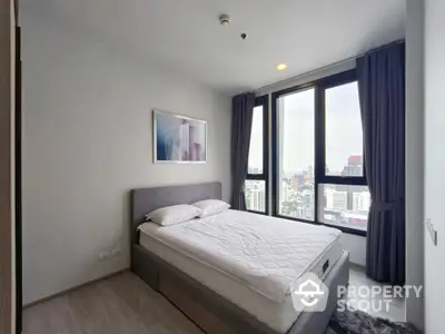 Modern bedroom with large windows offering stunning city views in high-rise apartment.