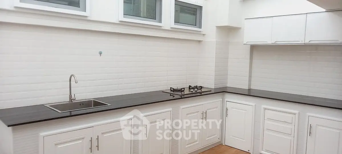 Modern kitchen with sleek countertops and gas stove in a bright, white interior.