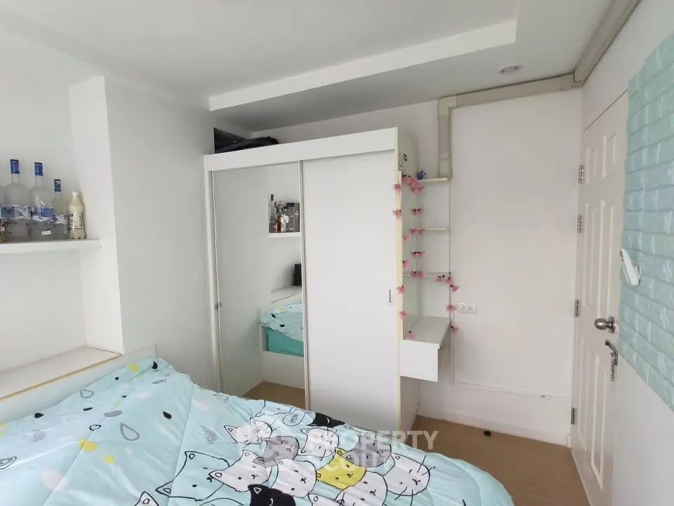 Cozy bedroom with mirrored wardrobe and cat-themed bedding in modern apartment.