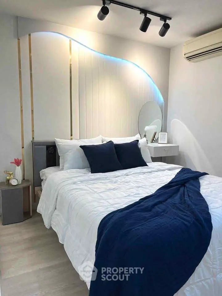 Modern bedroom with stylish lighting and cozy bedding in a contemporary apartment.