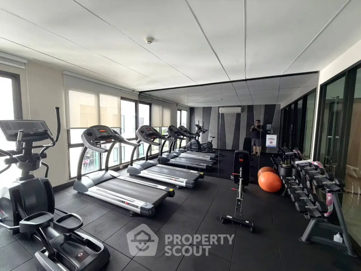 Modern gym with treadmills, weights, and exercise equipment in a bright, spacious room.