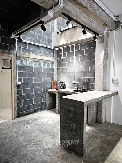 Modern industrial kitchen with concrete countertops and exposed brick walls