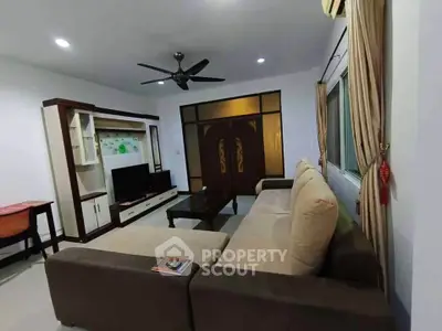 Spacious living room with modern furniture and ceiling fan in a cozy apartment.