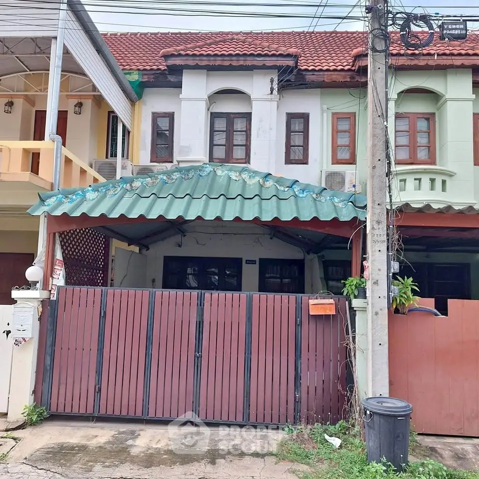 Charming townhouse with gated entrance and tiled roof in a cozy neighborhood.