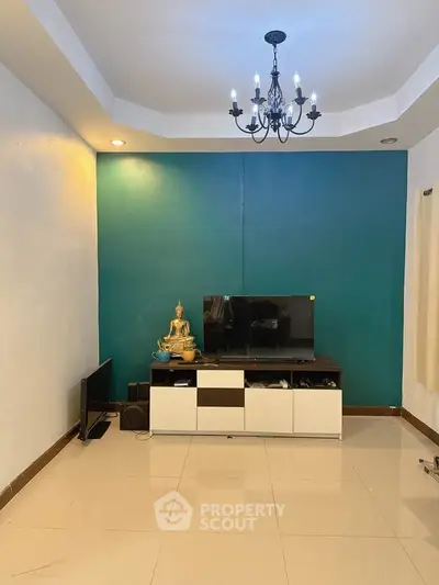 Modern living room with teal accent wall and elegant chandelier