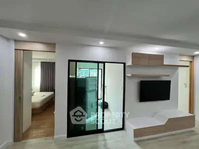 Modern apartment interior with sleek living room and bedroom view, featuring minimalist design and built-in TV unit.