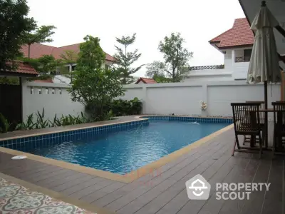 Inviting private pool with elegant wooden deck and cozy outdoor dining area, surrounded by lush greenery and a serene ambiance, perfect for relaxation and entertainment.