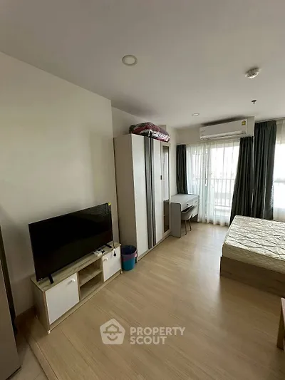 Modern bedroom with TV, wardrobe, and natural light from large windows.