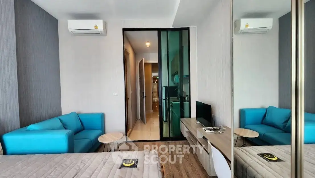 Modern studio apartment with blue sofa and mirrored wardrobe