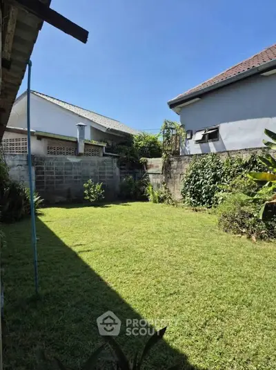 Charming backyard with lush green lawn and surrounding walls, perfect for outdoor activities and relaxation.
