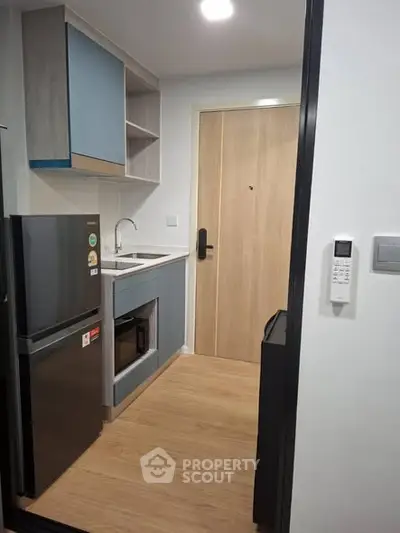 Modern compact kitchen with sleek appliances and wood flooring