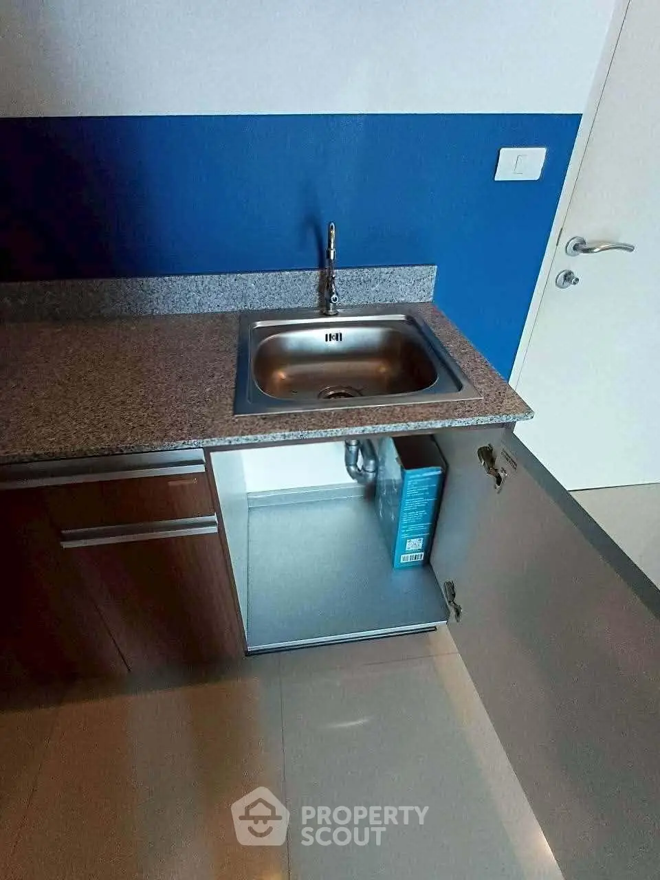 Modern kitchen with sleek granite countertop and stainless steel sink, featuring a minimalist design and elegant cabinetry.