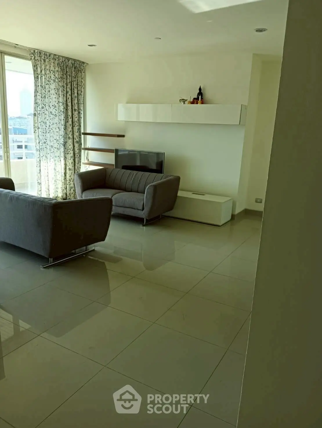 Spacious living room with modern furniture and large windows offering city views.