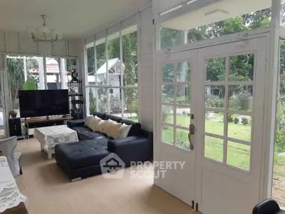 Charming living room with garden view, featuring elegant decor and ample natural light through large windows.