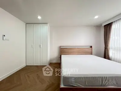 Modern minimalist bedroom with wooden flooring and large window