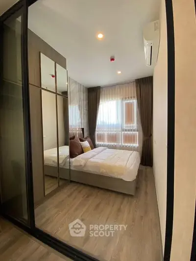 Modern bedroom with wooden flooring, large window, and mirrored wardrobe in a stylish apartment.