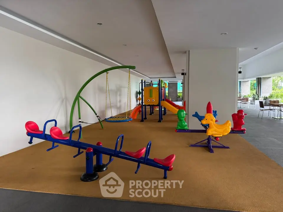 Spacious indoor playground with colorful equipment in modern residential building.