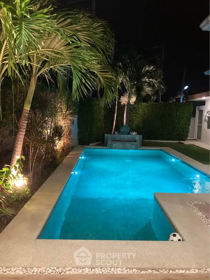 Luxurious night view of a private backyard pool with palm trees and ambient lighting.