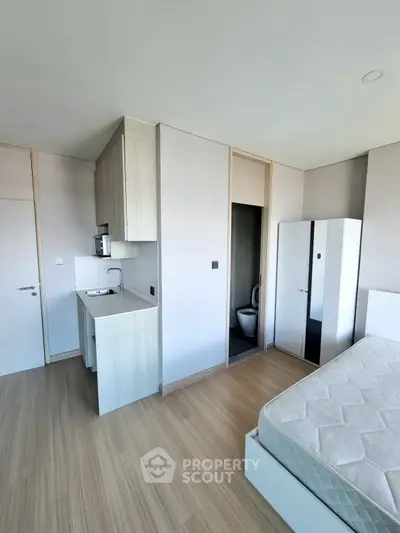 Modern studio apartment with compact kitchen and cozy sleeping area, featuring sleek design and natural light.