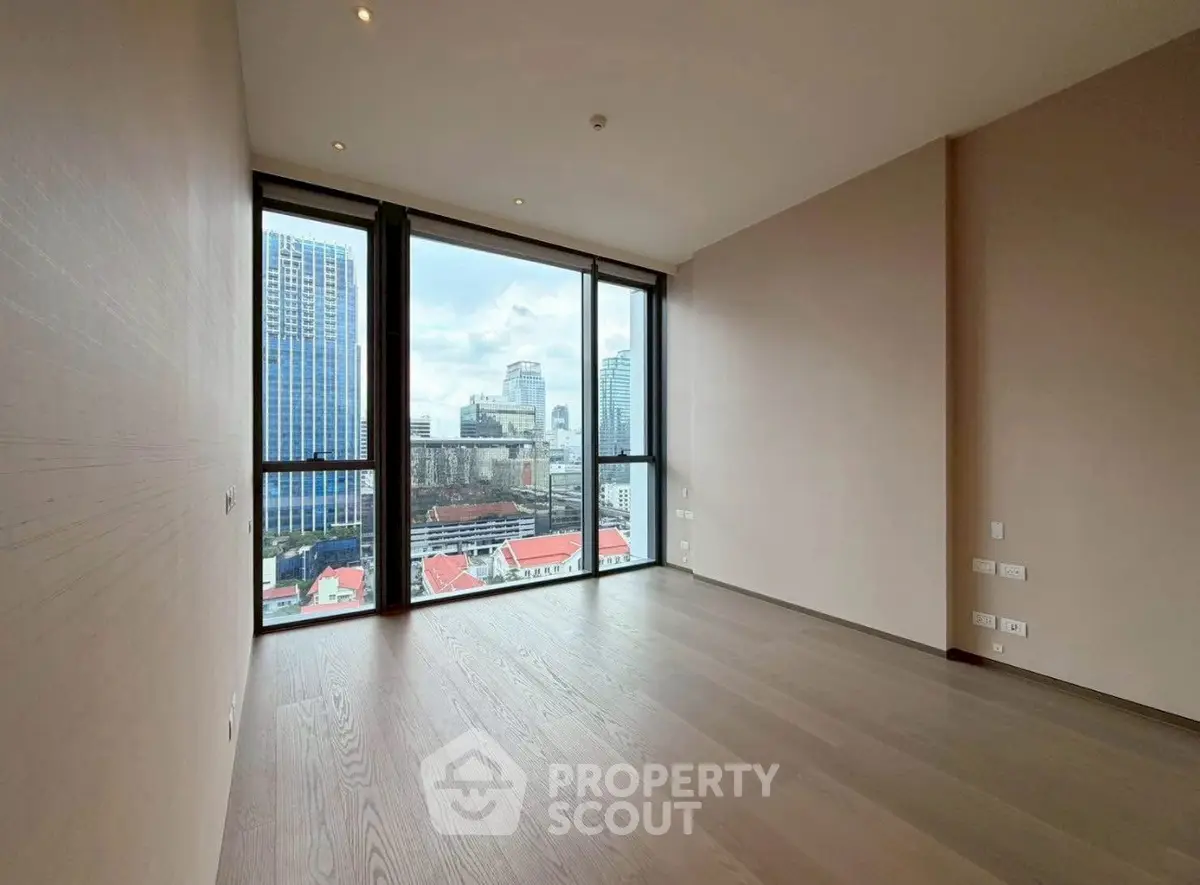 Spacious modern room with floor-to-ceiling windows offering stunning city views.