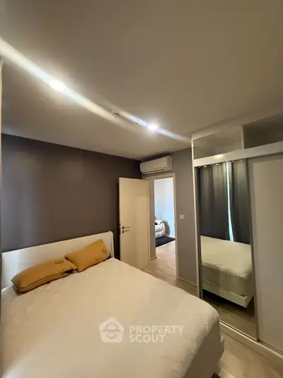 Cozy bedroom with mirrored wardrobe and modern lighting in stylish apartment.