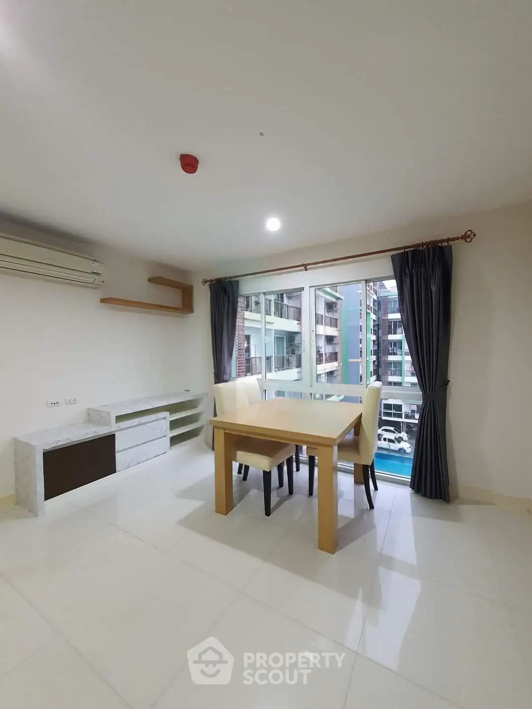 Spacious dining area with modern furniture and large window offering a view of the cityscape.