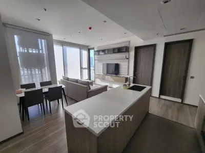Modern open-plan living room with sleek kitchen and dining area, featuring contemporary furniture and large windows.
