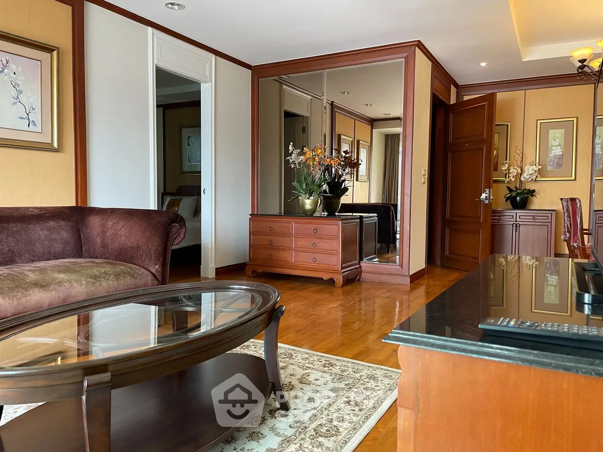 Elegant living room with wooden furniture and glass coffee table in a luxurious apartment.