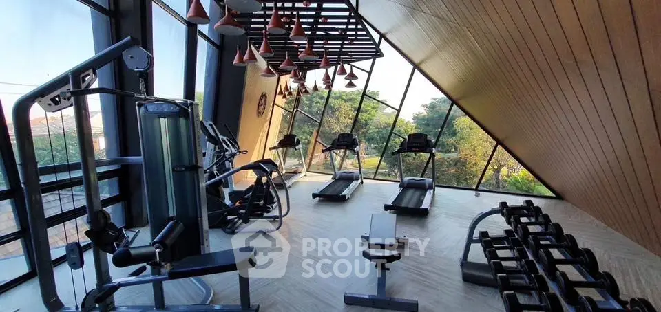 Modern gym with large windows and state-of-the-art equipment in a luxury building.