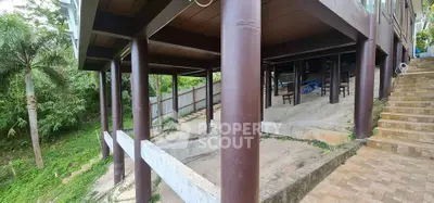 Elevated house structure with sturdy pillars and lush greenery surroundings