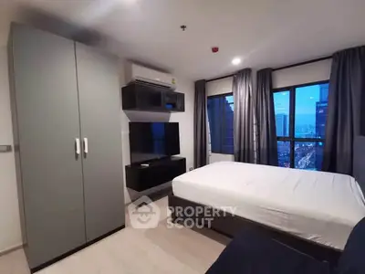 Modern bedroom with city view, featuring sleek furniture and large windows.