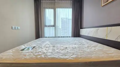 Spacious bedroom with large window and modern decor in a high-rise apartment.