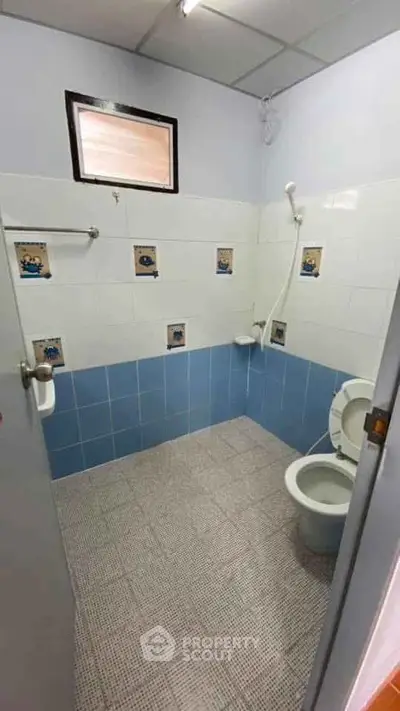 Compact bathroom with blue and white tiles, featuring a shower and toilet.