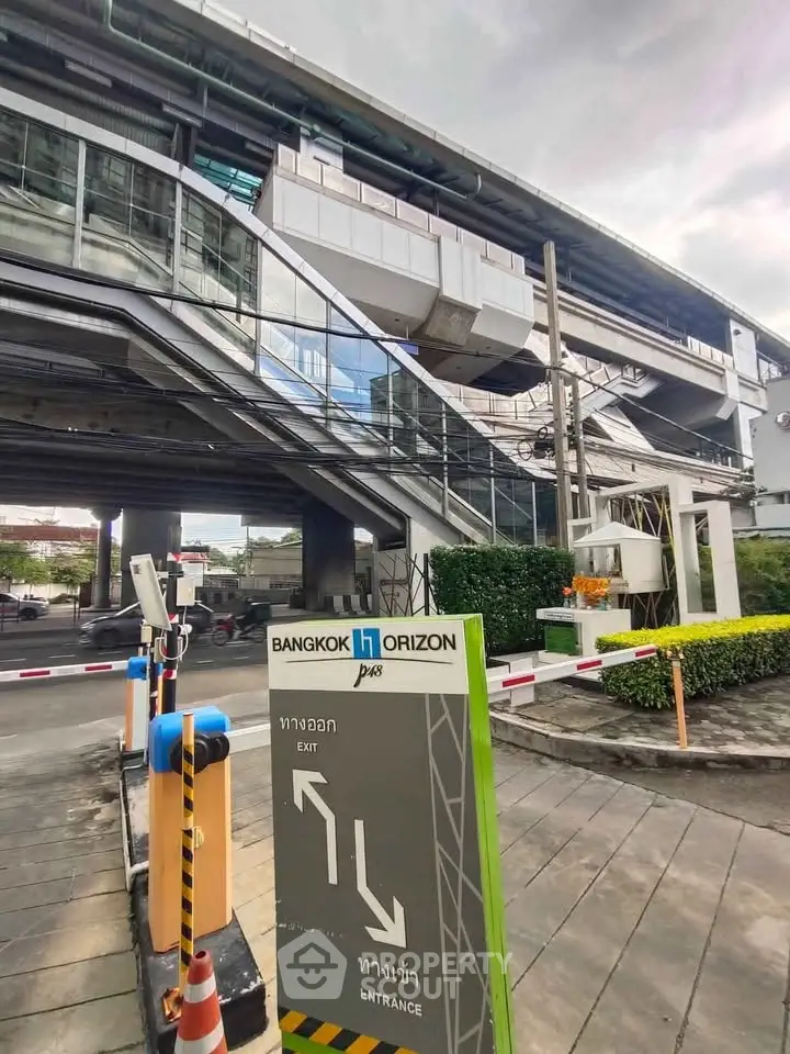 Modern Bangkok building exterior with entrance sign and urban surroundings.