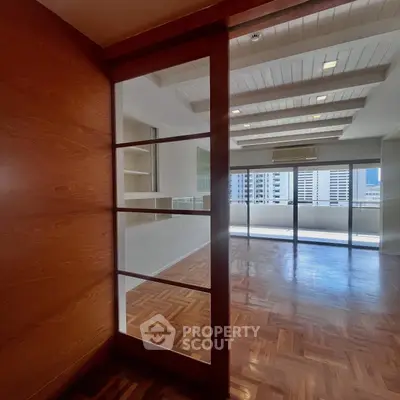 Spacious living room with parquet flooring and large windows offering city views.