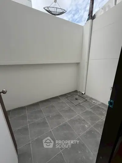 Minimalist outdoor patio with tiled flooring and white walls, perfect for a cozy urban retreat.