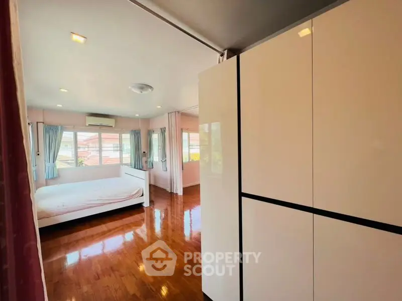 Spacious bedroom with wooden flooring and ample natural light