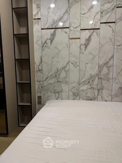 Luxurious bedroom with elegant marble accent wall and sleek shelving unit.