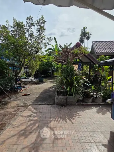 Charming garden patio with lush greenery and tiled pathway in a serene residential setting.
