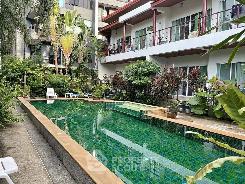 Inviting tropical oasis with a sparkling pool surrounded by lush greenery, nestled within a modern residential complex.