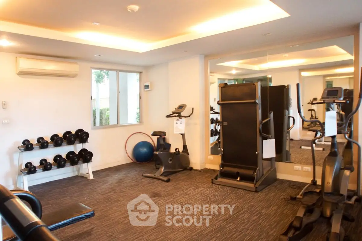 Modern gym with exercise equipment and mirrored walls in a residential building.