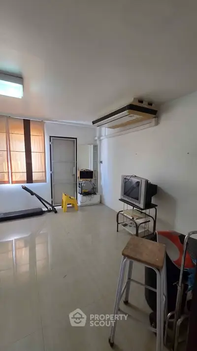 Spacious living room with natural light and vintage TV setup